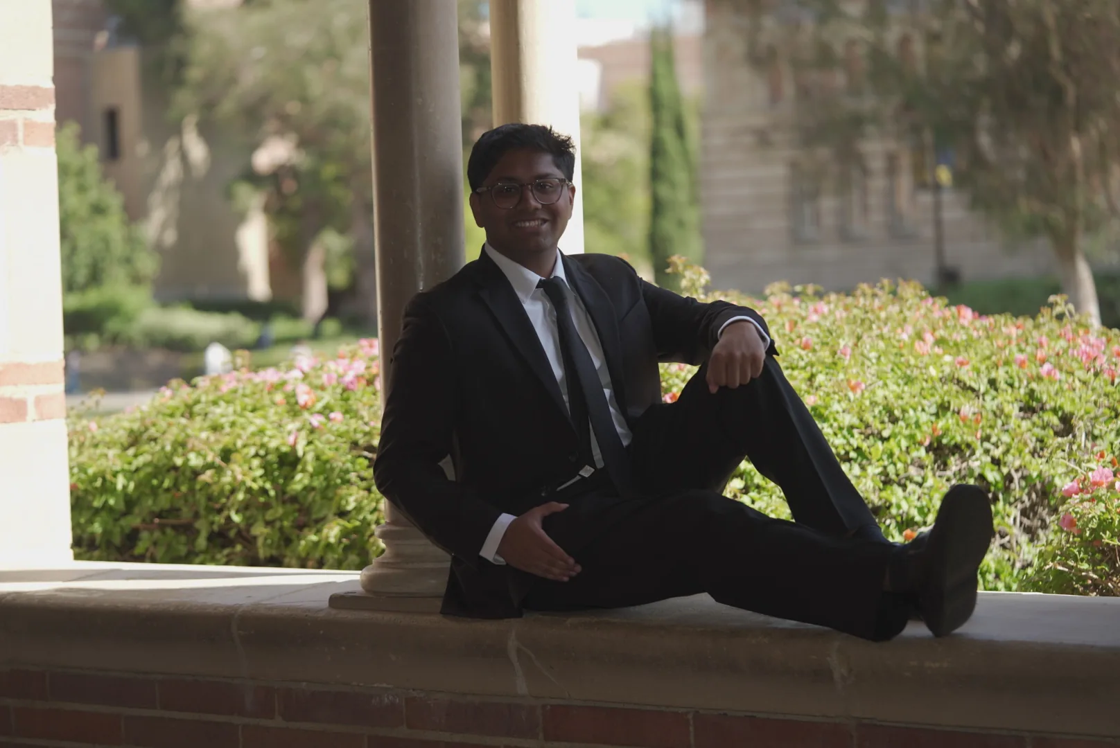 UCLA graduate seated beneath a campus arch